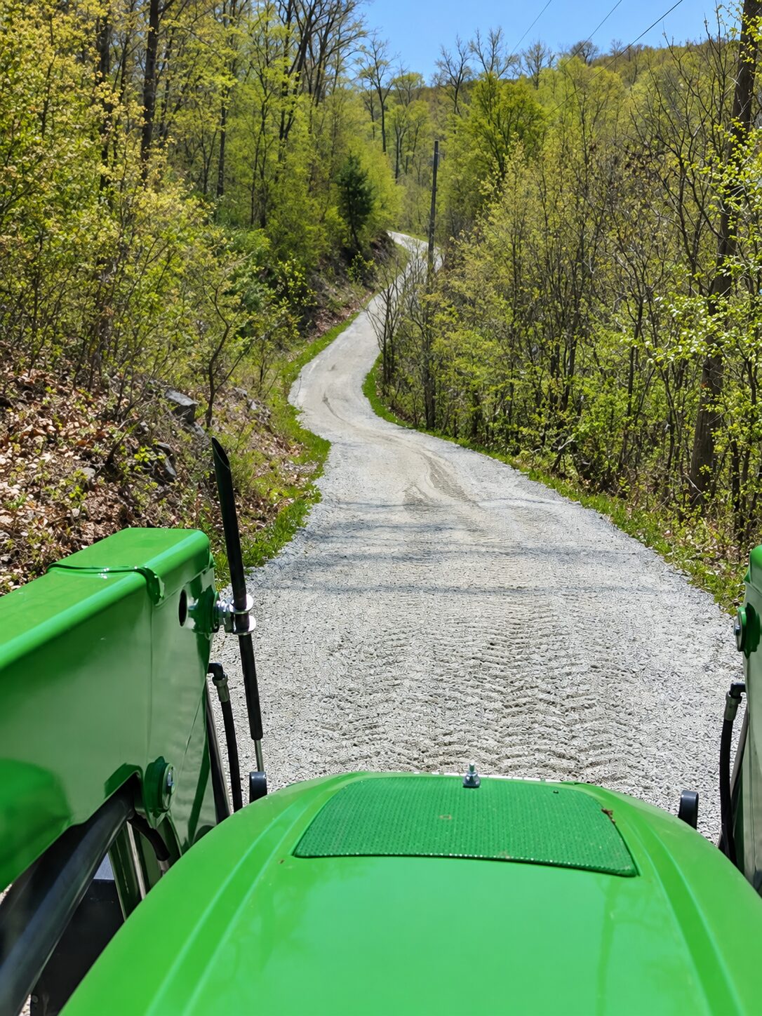Tractor grading a winding gravel woodland road