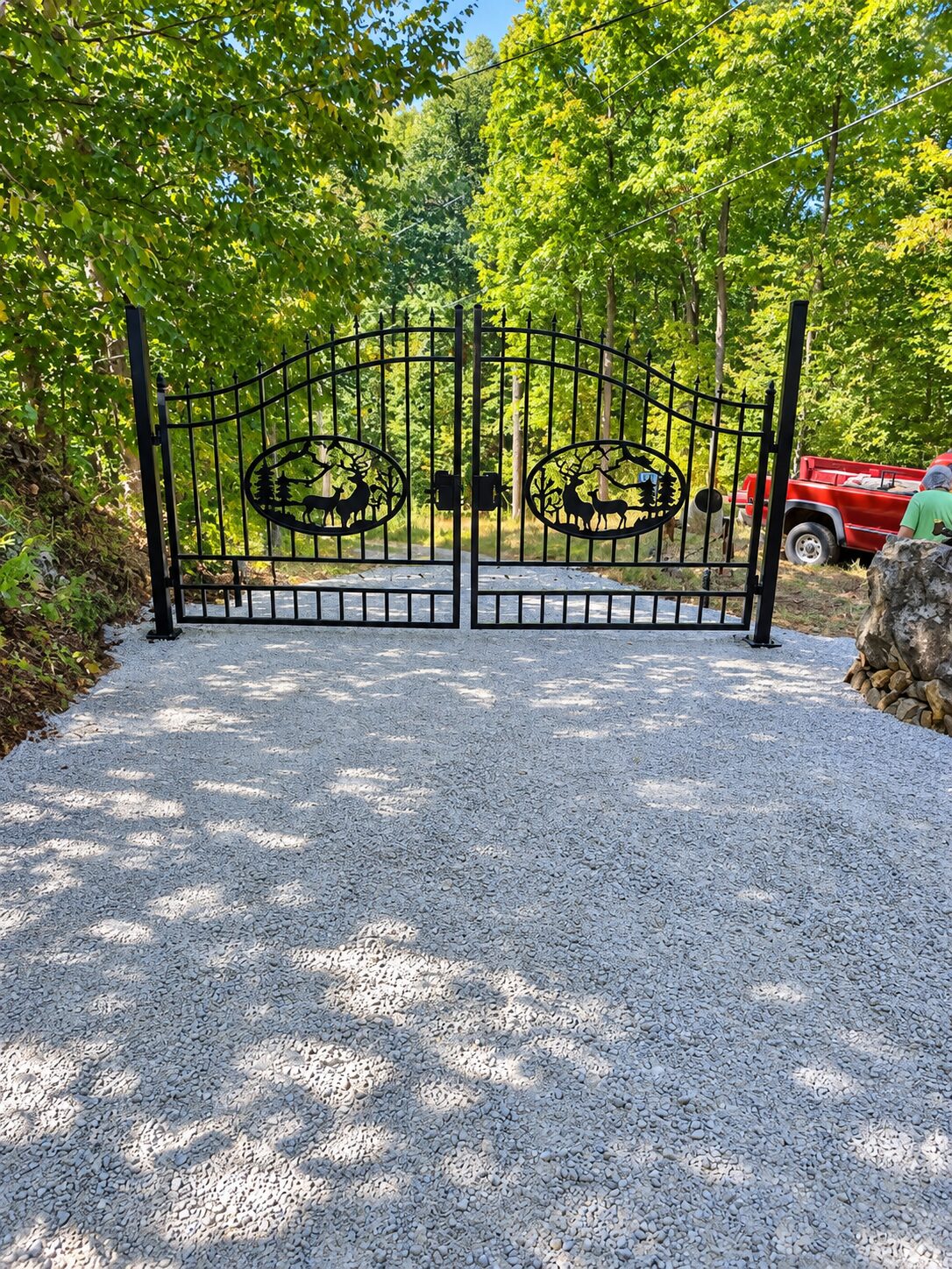 Timber entrance gate with elk medallions at a cleared forest driveway